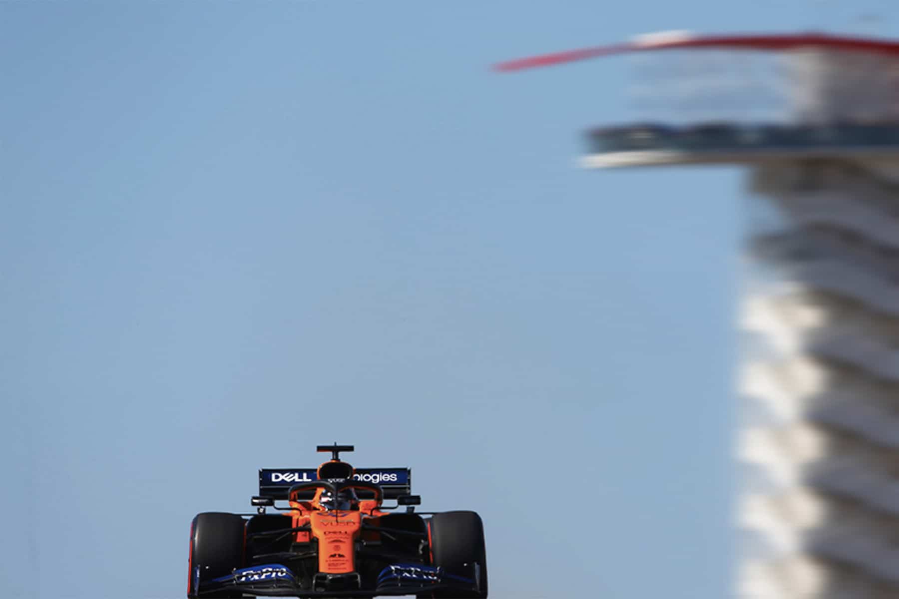 One of the McLaren cars roars past the Circuit of the Americas tower.