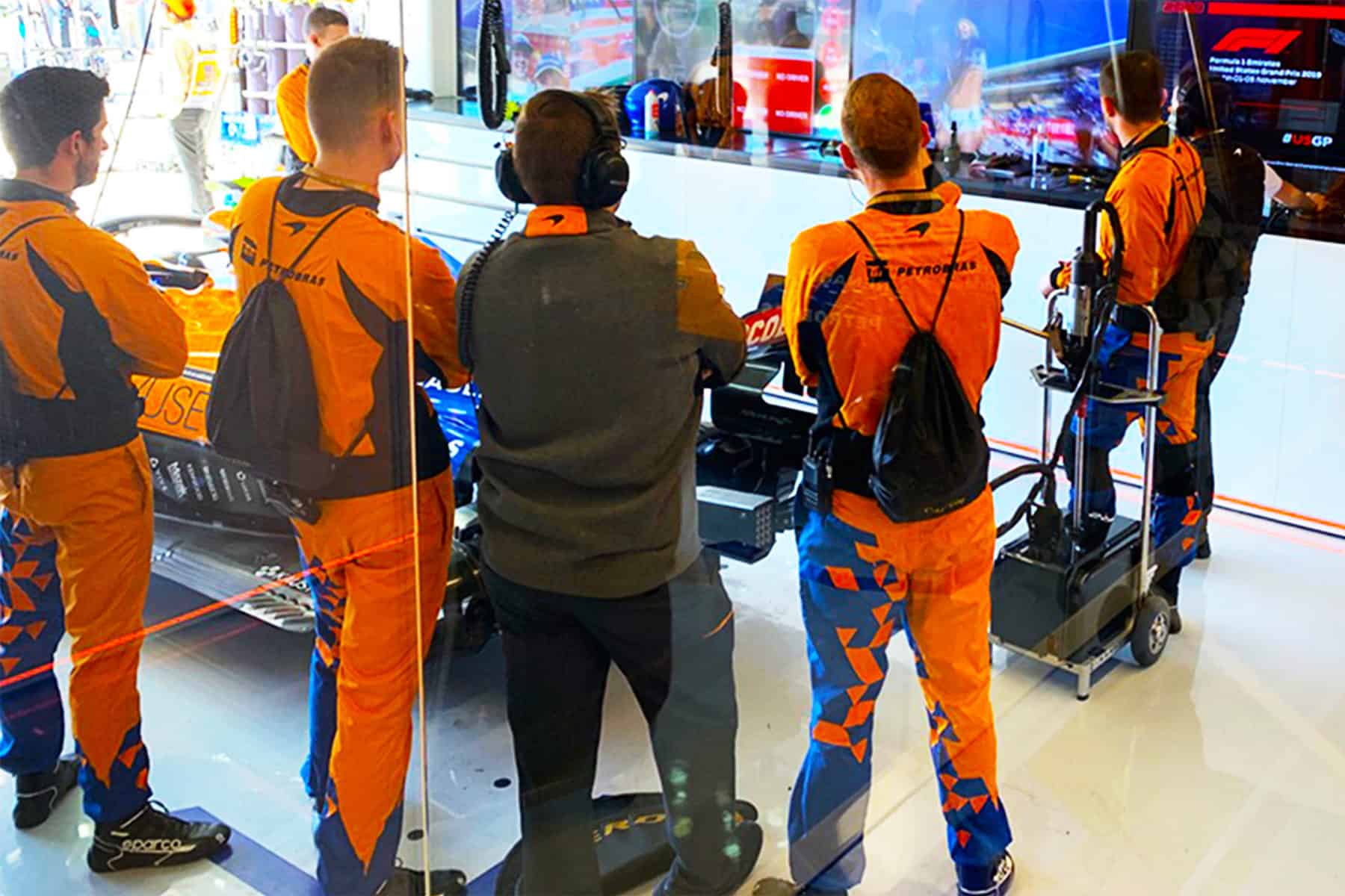 The McLaren garage crew takes a short break from race prep to check out the cheerleaders on screen.